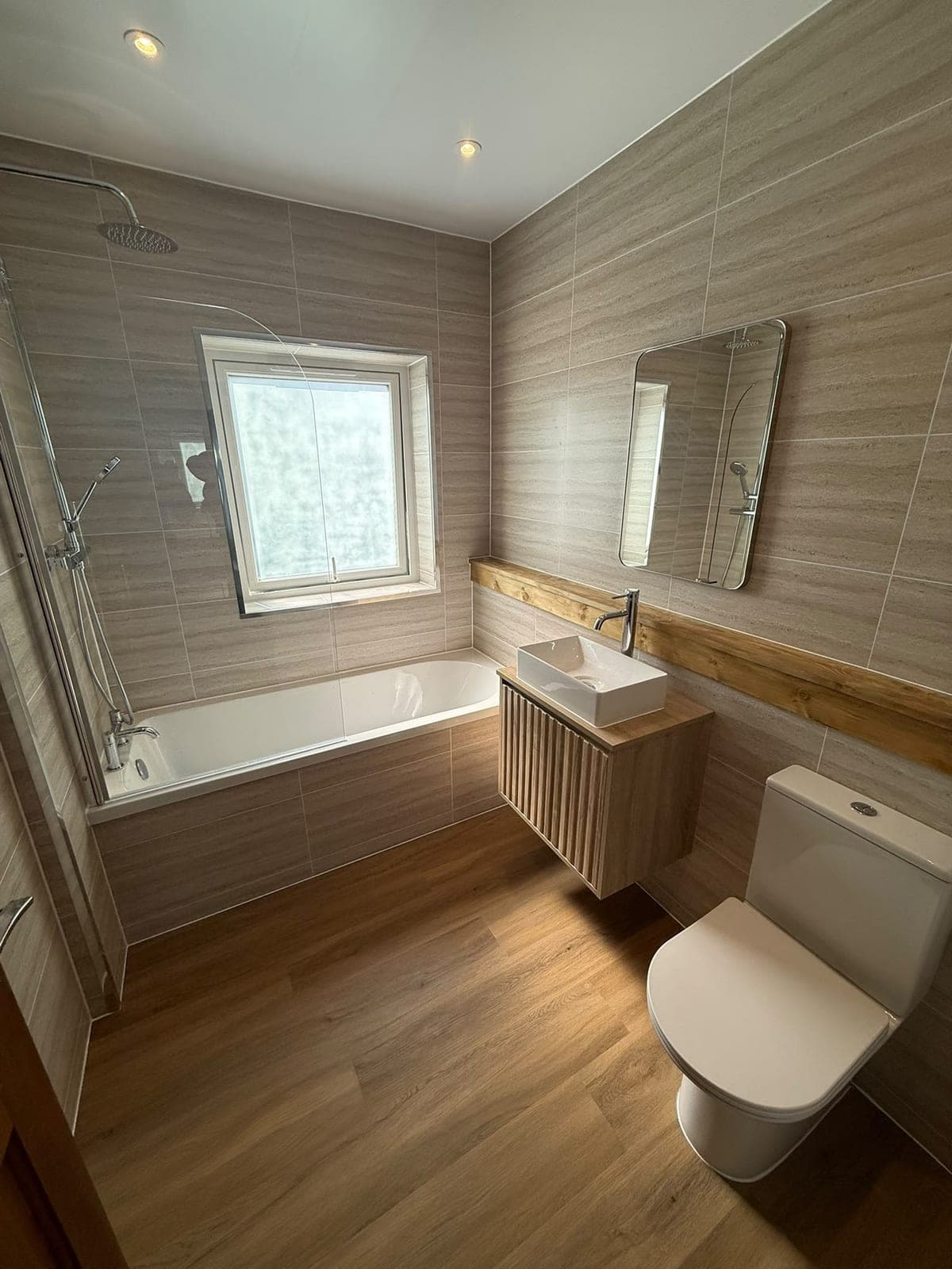 Kirkcaldy bathroom with a bath, rainfall shower over and stone-effect tiling