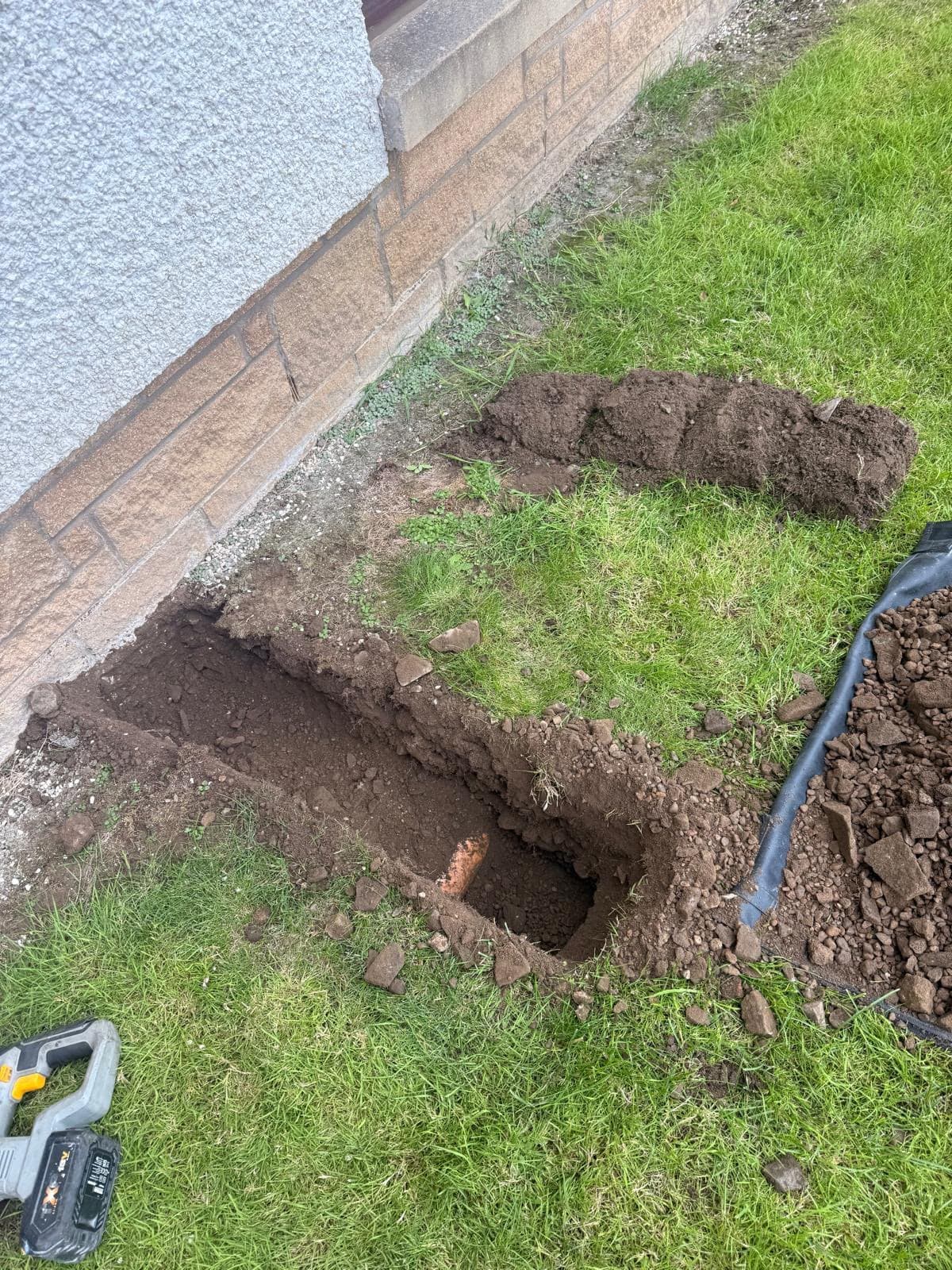 Trench dug along a Livingston house wall to run a boiler condensate pipe underground to a drain