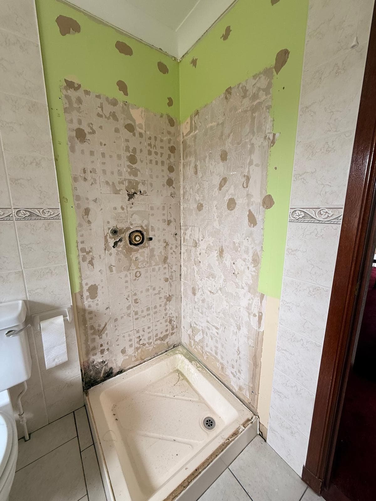 Old shower alcove in Kirkcaldy before replacement, with the tiles stripped and mould around the tray